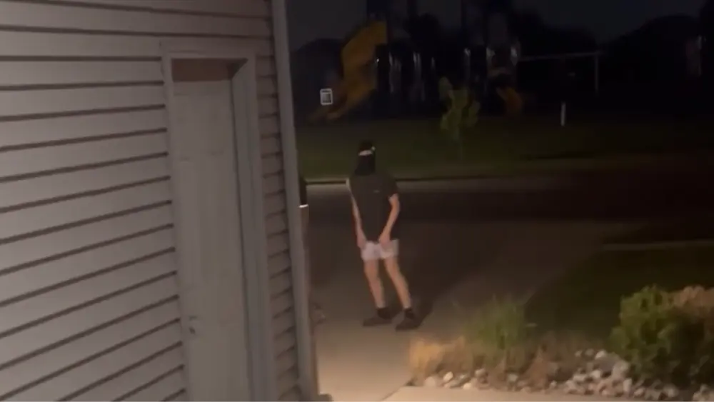 Still image of video showing one of the kids in a ski mask in the driveway