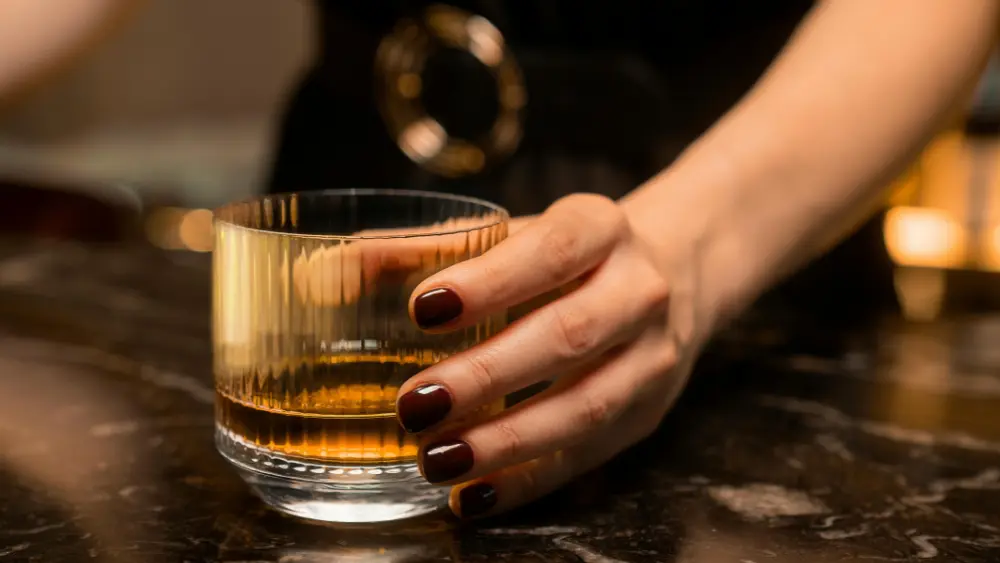 Image of woman's hand holding a drink at a bar