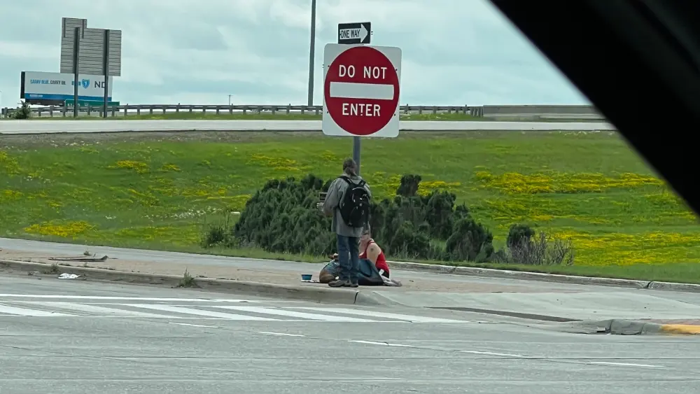 Image of people loitering on the sidewalk sitting next to a "DO NOT ENTER" sign just off I-29 in south Fargo