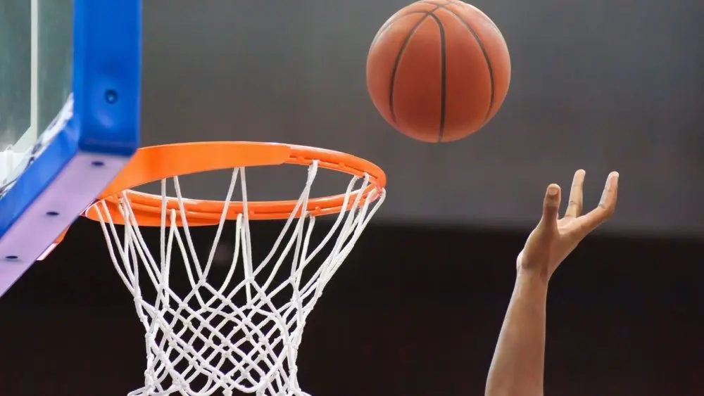 Orange basketball ball flying into the basketball hoop