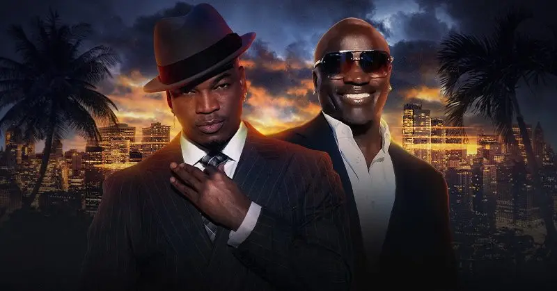 a picture of ne-yo and akon dressed in suits with a sunset skyline behind them