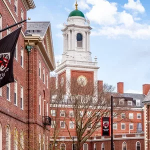 View of the architecture of the famous Harvard University in Cambridge^ Massachusetts^ USA showcasing it brick buildings with some students and locals passing by . Cambridge^ MA^ USA - March 15^ 2024