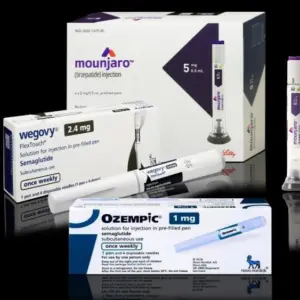 Injection pens and packaging boxes of weight-loss and type 2 diabetes medication Mounjaro^ Wegovy^ Ozempic^ Zepbound Isolated on black background with reflections.