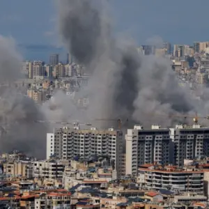 Multiple large plumes of thick grey smoke billow from residential apartment complexes following an explosion or missile strike in a crowded urban skyline. Jan 3 2021 in Iran