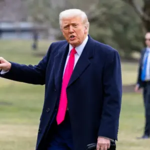 President Donald Trump points while on the South Lawn as he walks into the White House. WASHINGTON – February 22^ 2025