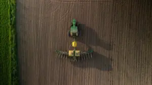 Ontario Canada May 13 2022: Aerial view of a large modern John Deere tractor plowing farmland field in spring season. Drone photo. Farming^ agriculture concept.