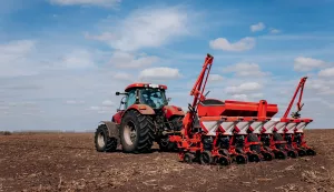 spring-sowing-season-farmer-with-a-tractor-sows-corn-seeds-on-his-field-planting-corn-with-trailed-planter-farming-seeding-the-concept-of-agriculture-and-agricultural-machinery