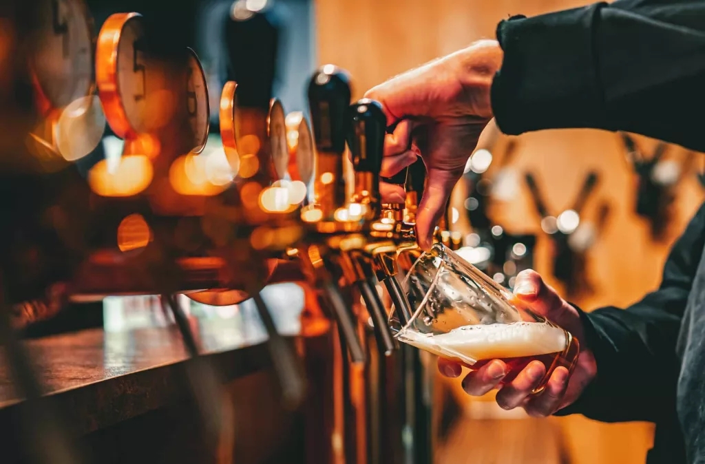 bartender-hand-at-beer-tap-pouring-a-draught-beer-in-glass-servi