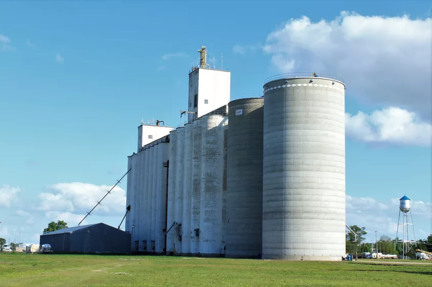 grain-silos-on-a-co-op-grain-elevator-in-nickerson-kansas-usa-with-green-grass-and-blue-sky-on-a-colorful-day