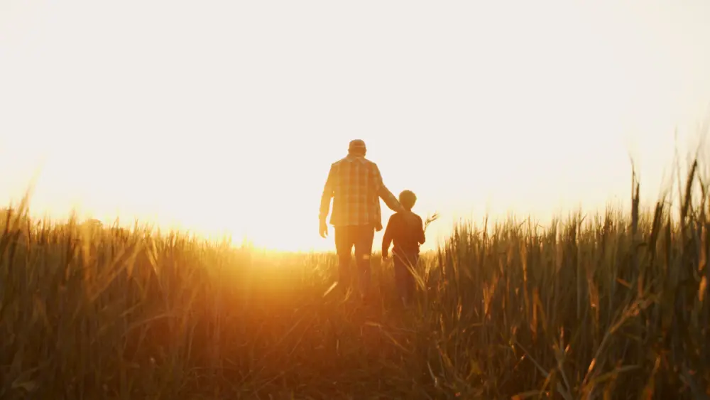 farmer-and-his-son-in-front-of-a-sunset-agricultural-landscape-man-and-a-boy-in-a-countryside-field-fatherhood-country-life-farming-and-country-lifestyle