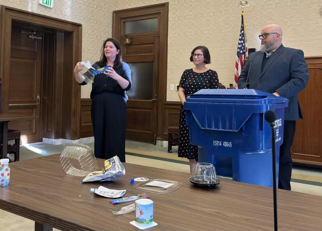 Rep. Liz Berry, D-Seattle, shows the different types of containers that her family’s fruit came in this week. Berry, along with Sen. Liz Lovelett, D-Anacortes, and Dylan de Thomas, at the Recycling Partnership, spoke to reporters about a new bill to require manufacturers to pay for recycling. (Photo by Laurel Demkovich/Washington State Standard)