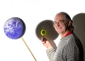 Guy Worthey demonstrates how an eclipse works using different-sized balls as the planets and sun. (Photo by WSU Photo Services)