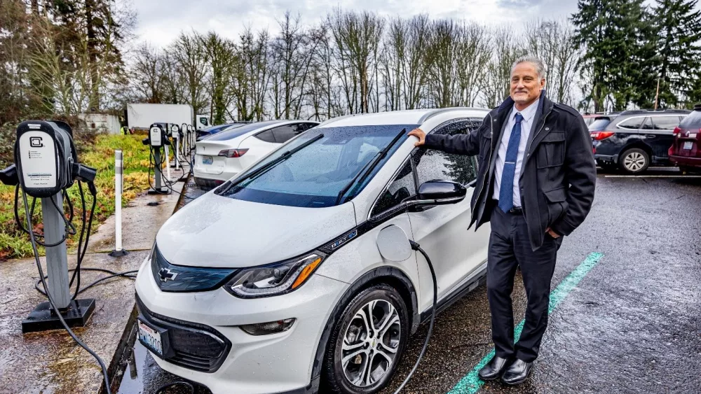 Sen. Jeff Wilson, R-Longview, one of several members of the Legislature who drive electric vehicles, juices up his Chevy Bolt in a legislative parking lot. /Credit: Washington State Senate.