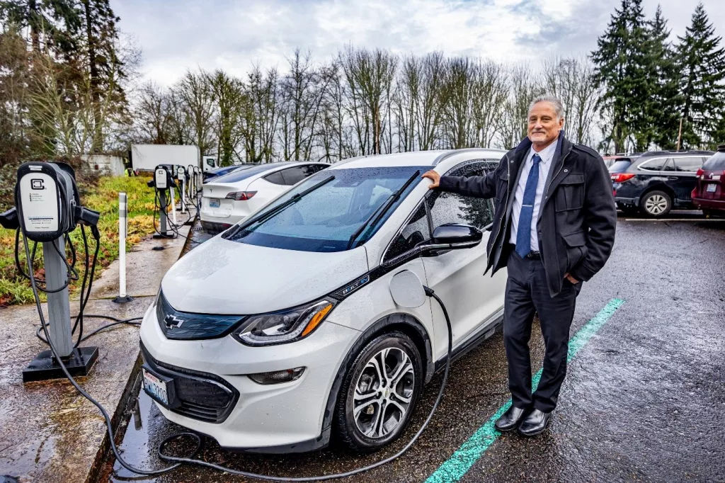 Sen. Jeff Wilson, R-Longview, one of several members of the Legislature who drive electric vehicles, juices up his Chevy Bolt in a legislative parking lot. /Credit: Washington State Senate.