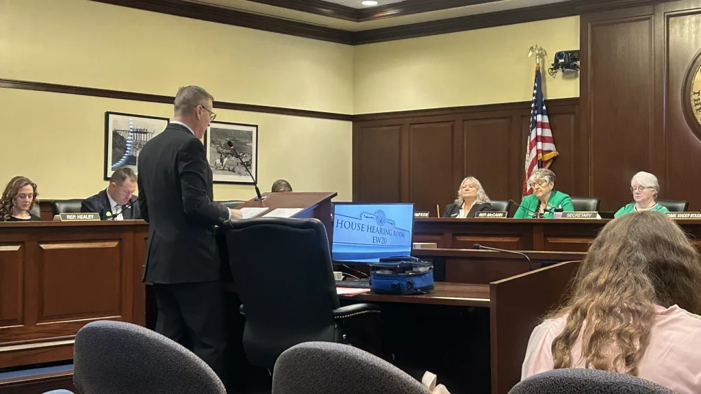 Jeremy Kitzhaber speaks to the Idaho House Health and Welfare Committee to advocate for medical marijuana. He previously served in the U.S. Air Force as a civil engineer and first sergeant. He has stage four cancer, which he developed while transporting radioactive materials in the military. In the blue bag to his right, he stores opioids, anti-anxiety medication and Narcan. (Photo by Mia Maldonado/Idaho Capital Sun) Jeremy Kitzhaber, a