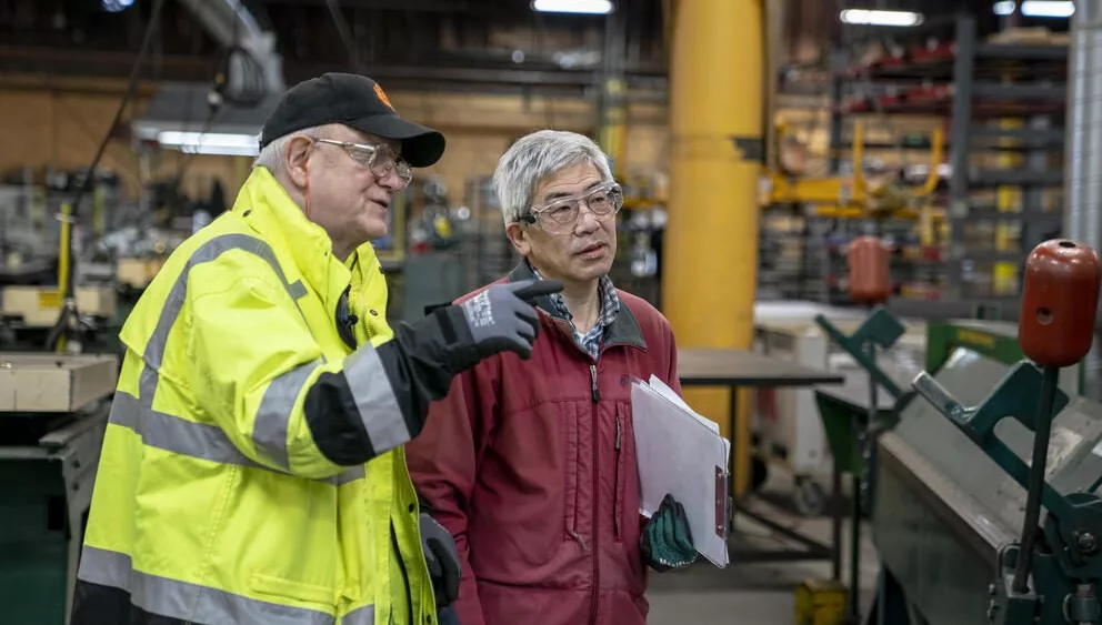 J.C. Smith, left, a safety and health consultant with the Washington State Department of Labor and Industries, chats with colleague Dan Chan during a proactive safety consultation in 2023. (David Ryder for Cascade PBS)