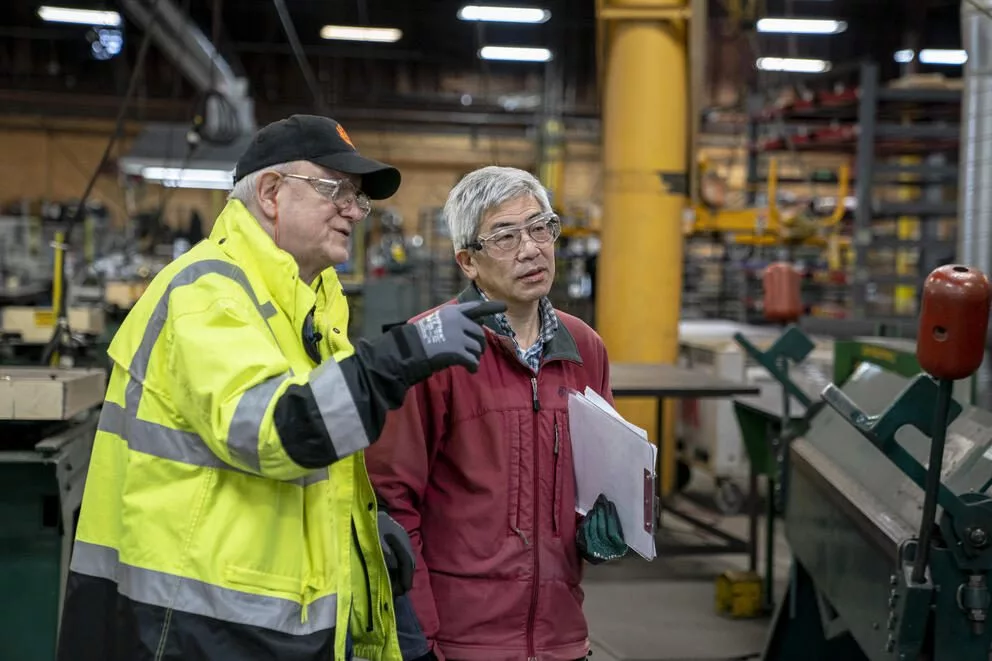 J.C. Smith, left, a safety and health consultant with the Washington State Department of Labor and Industries, chats with colleague Dan Chan during a proactive safety consultation in 2023. (David Ryder for Cascade PBS)