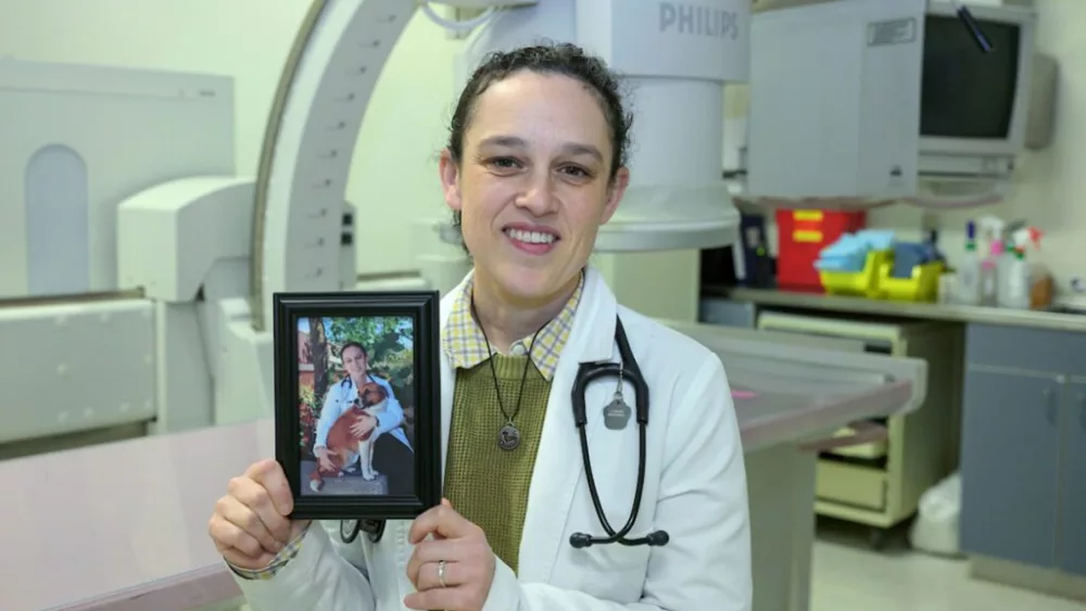 Jillian Haines of the Veterinary Teaching Hospital in Washington State University's College of Veterinary Medicine poses for a photo as she holds a picture of her with her dog Cake. Cake had a condition known as megaesophagus which inspired Haines’ research and academic focus (photo by College of Veterinary Medicine/Ted S. Warren).