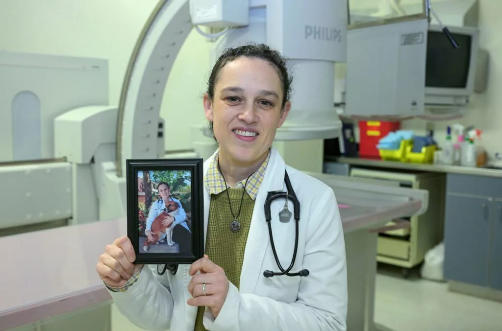 Jillian Haines of the Veterinary Teaching Hospital in Washington State University's College of Veterinary Medicine poses for a photo as she holds a picture of her with her dog Cake. Cake had a condition known as megaesophagus which inspired Haines’ research and academic focus (photo by College of Veterinary Medicine/Ted S. Warren).