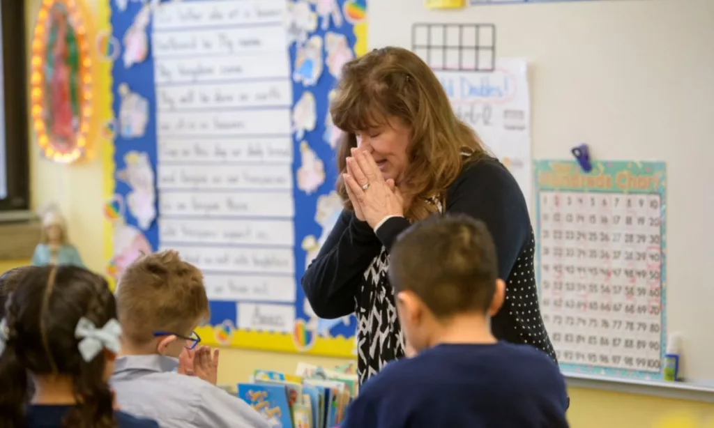 A teacher prayed with students in a Chicago Catholic school. The private system’s superintendent is among those who are wary of the implications of religious charter schools. (Archdiocese of Chicago Catholic Schools)