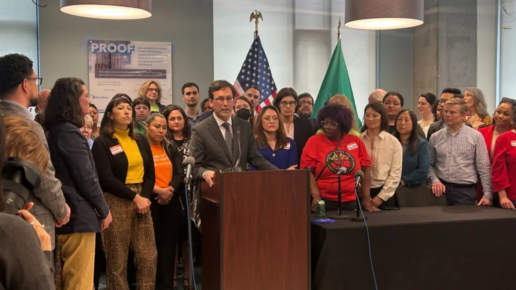 Gov. Bob Ferguson, podium, makes remarks during a bill signing event on May 7, 2025, where he signed a law that will cap rent increases for many residential tenants across Washington at 10% or less annually. (Photo by Jake Goldstein-Street/Washington State Standard)