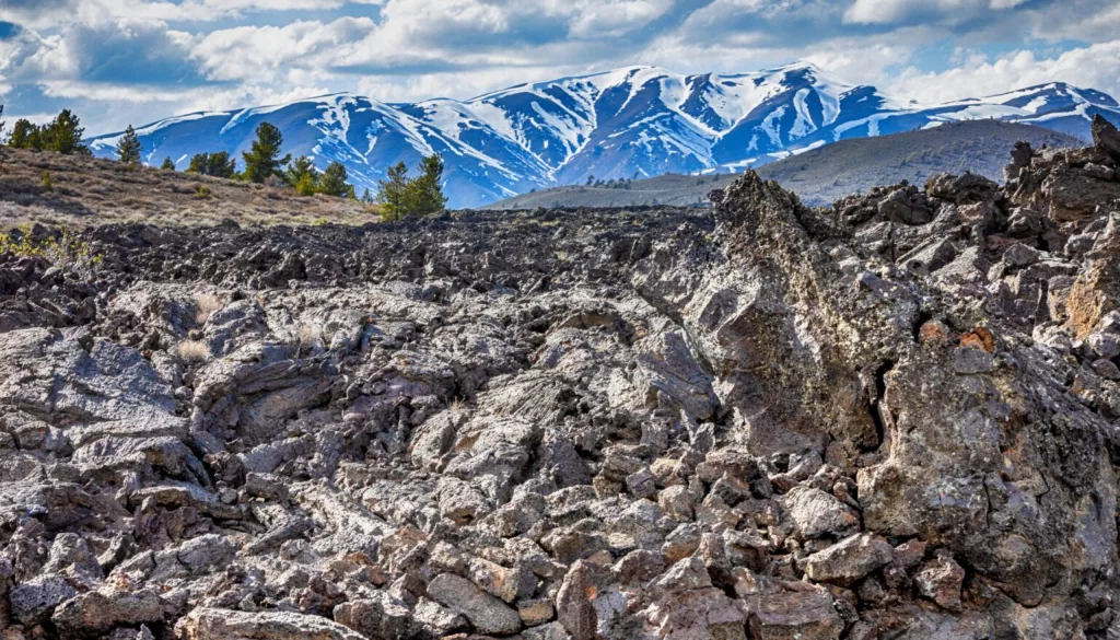 A lava field can be seen with the Pioneer Mountains in the background on April 29, 2024, at Craters of the Moon National Monument and Preserve near Arco. On May 2, 1924, President Calvin Coolidge designated 54,000 acres of volcanic landscape across southern Idaho a national monument, adding that the landscape has “curious and unusual phenomena of great educational value.” (Pat Sutphin for the Idaho Capital Sun)
