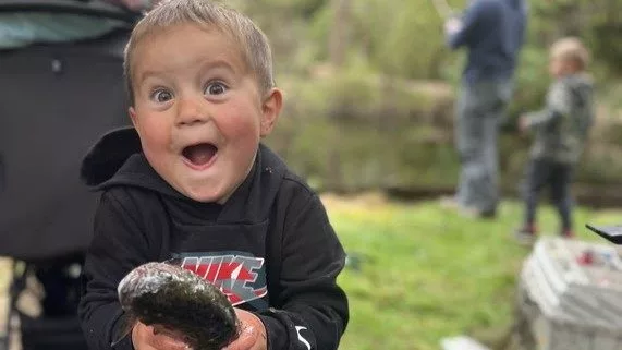 A young child holds his first trout while smiling big for the camera. Photo credit: Erin Hawkinson