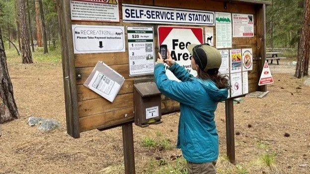 A hiker scans a QR code using Scan and Pay at a campground on the Okanogan-Wenatchee National Forest. Photo courtesy U.S. Forest Service.