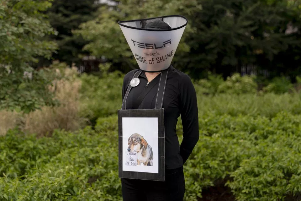 Yvette Blauvelt, who owns a Tesla, poses for a portrait during a Tesla protest at University Village in Seattle, Washington on May 3, 2025. Blauvelt is conflicted about owning her Tesla, and wore a “Tesla owner’s cone of shame.” (David Ryder for Cascade PBS)
