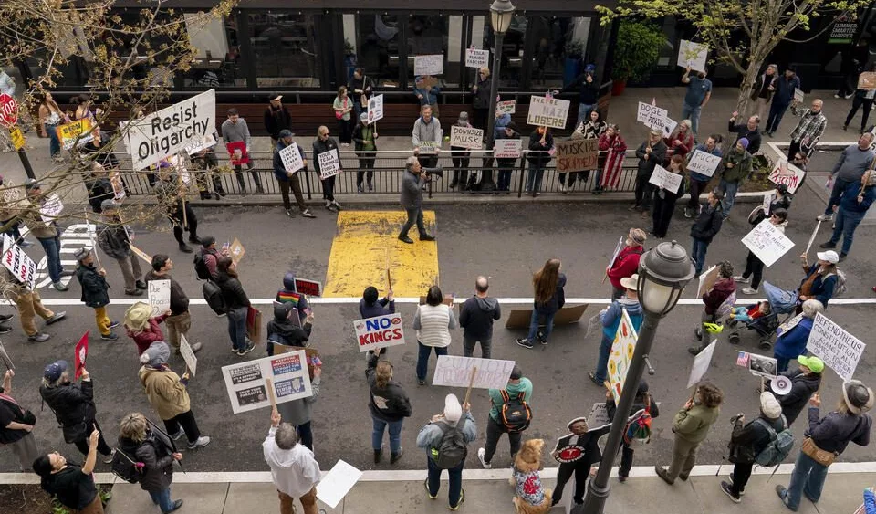 Demonstrators listen as Devin Hermanson leads a Tesla protest at University Village in Seattle, Washington on May 3, 2025. Tesla protests have had a major impact on the company and its sales in the Seattle area. (David Ryder for Cascade PBS)