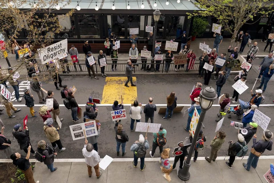 Demonstrators listen as Devin Hermanson leads a Tesla protest at University Village in Seattle, Washington on May 3, 2025. Tesla protests have had a major impact on the company and its sales in the Seattle area. (David Ryder for Cascade PBS)