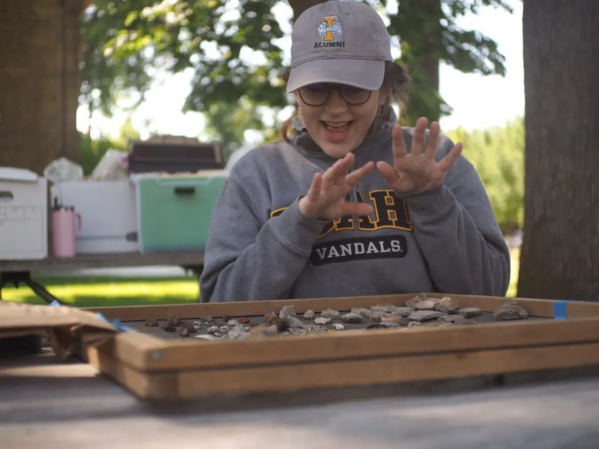 Sophie Streiff discusses rocks and artifacts sitting on a drying screen in her field lab. (Kaeden Lincoln/IdahoEdNews)