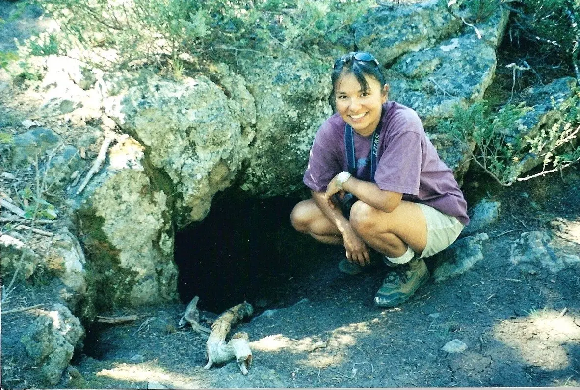 Marcie Carter, who began her career with Nez Perce Tribe’s wildlife division working on the wolf project, poses for a photo in front of a wolf den. (File photo courtesy of Marcie Carter)