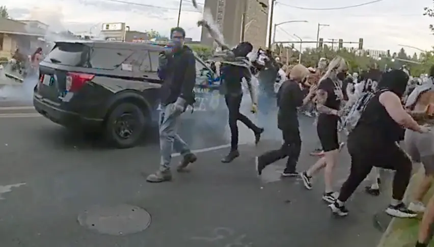 A protester throws a smoke canister back at Spokane police officers and sheriff deputies. Courtesy of a contributor to The Center Square.
