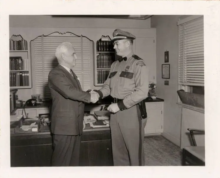 Lt. Charles Kinzel of the Washington State Patrol, right, shakes hands with Washington State College President Wilson Compton in 1950. Kinzel served on detached duty as chief of the newly organized Washington State College police force. (Photo courtesy of WSU Manuscripts, Archives & Special Collections)