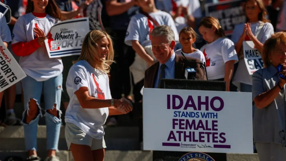 Riley Gaines, a former collegiate swimmer and national figure in the transgender athletics debate, shakes hands with Idaho Gov. Brad Little in August, after the Republican governor announced an executive order defending “fairness in women’s sports.” (Idaho EdNews photo)