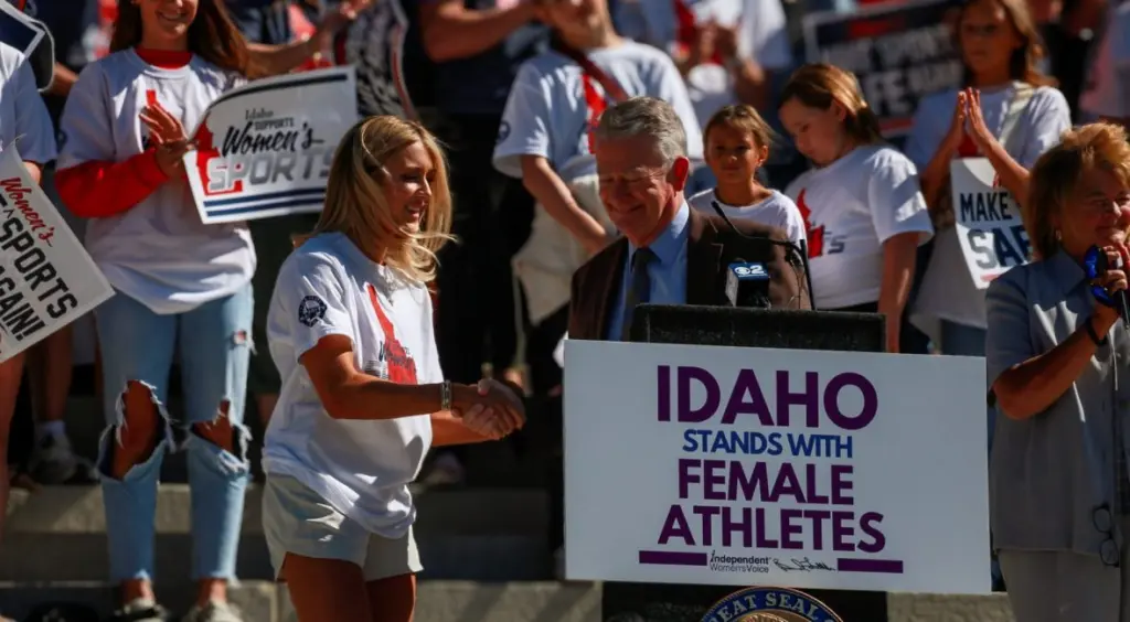 Riley Gaines, a former collegiate swimmer and national figure in the transgender athletics debate, shakes hands with Idaho Gov. Brad Little in August, after the Republican governor announced an executive order defending “fairness in women’s sports.” (Idaho EdNews photo)