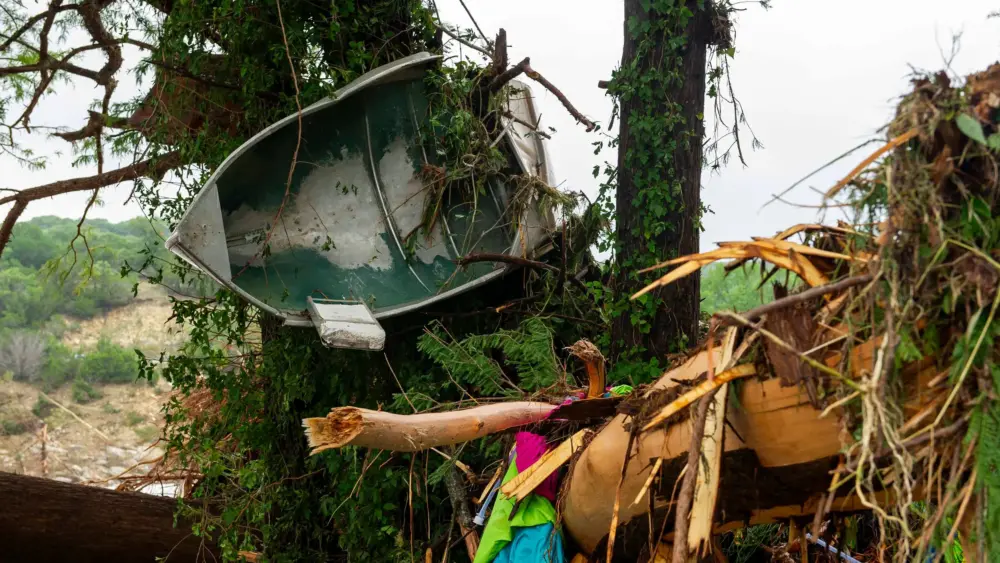 A small boat is wrapped around a tree along with other debris in Ingram on Saturday, July 5, 2025. Ingram is a small town about seven miles northwest of Kerrville. Credit: Ronaldo Bolaños/The Texas Tribune