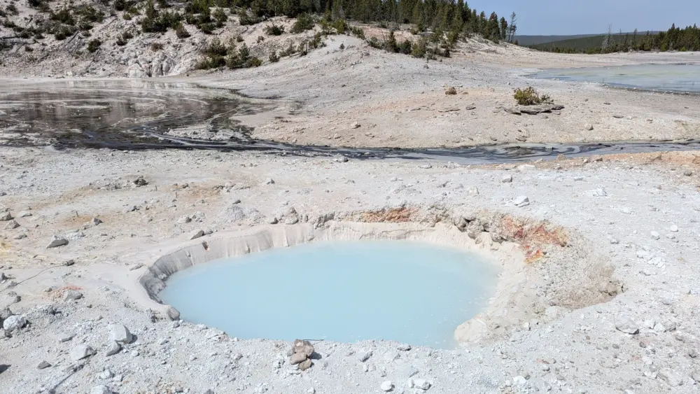 Sources/Usage: Public Domain. View Media Details View looking northwest at a new thermal pool in the Porcelain Basin area of Norris Geyser Basin, Yellowstone National Park, that probably formed in a series of mildly explosive events between late December 2024 and early February 2025. The rocks and white material (silica mud) surrounding the pool were probably ejected as the feature formed. The pool is about 4 meters (13 feet) across. U.S. Geological Survey photo by Mike Poland, May 12, 2025.