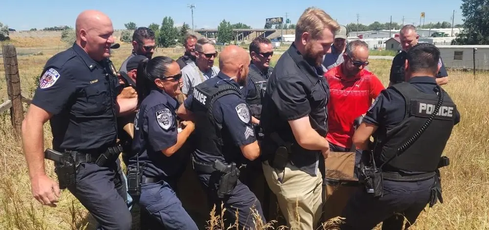 A yearling moose is barely visible as it is carried by City of Blackfoot police and animal control officers, Idaho Fish and Game personnel, and local Blackfoot residents to a trailer for transport out of town. On July 23, this moose and one other yearling moose were tranquilized and removed from a busy business center in Blackfoot and then relocated to suitable habitat away from people.