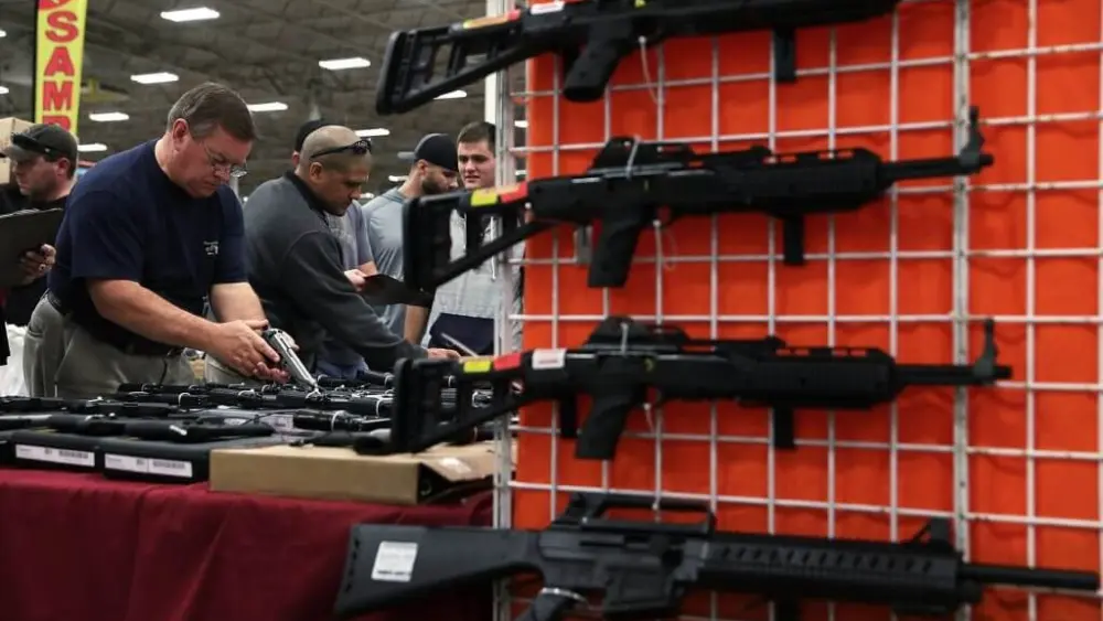 Potential buyers try out guns which are displayed on an exhibitor’s table during the Nation’s Gun Show on Nov. 18, 2016 at Dulles Expo Center in Chantilly, Virginia. (Photo by Alex Wong/Getty Images)