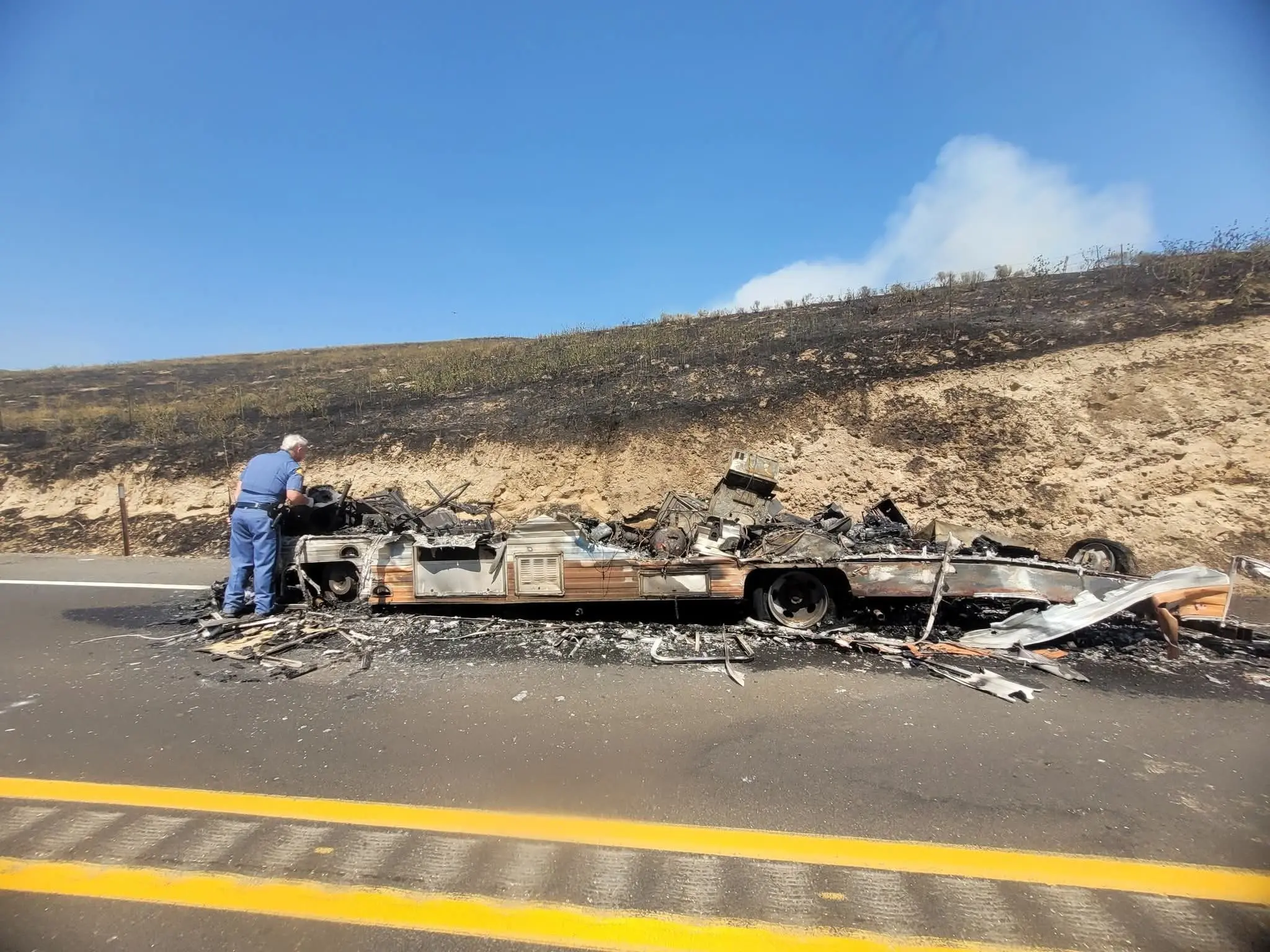 WSP Tooper Examines Remnants Of Motorhome That Caught Fire On SR127 Sparking The Large Blaze