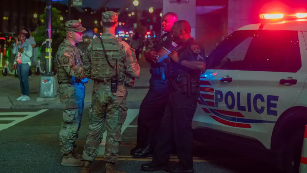 Army 2nd Lt. Harry Siegel and Sgt. 1st Class Nikolay Bashko, both assigned to Joint Task Force District of Columbia as part of the D.C. Safe and Beautiful Task Force, talk with Metropolitan Police Department officers near Nationals Park in Washington, Aug. 19, 2025.
