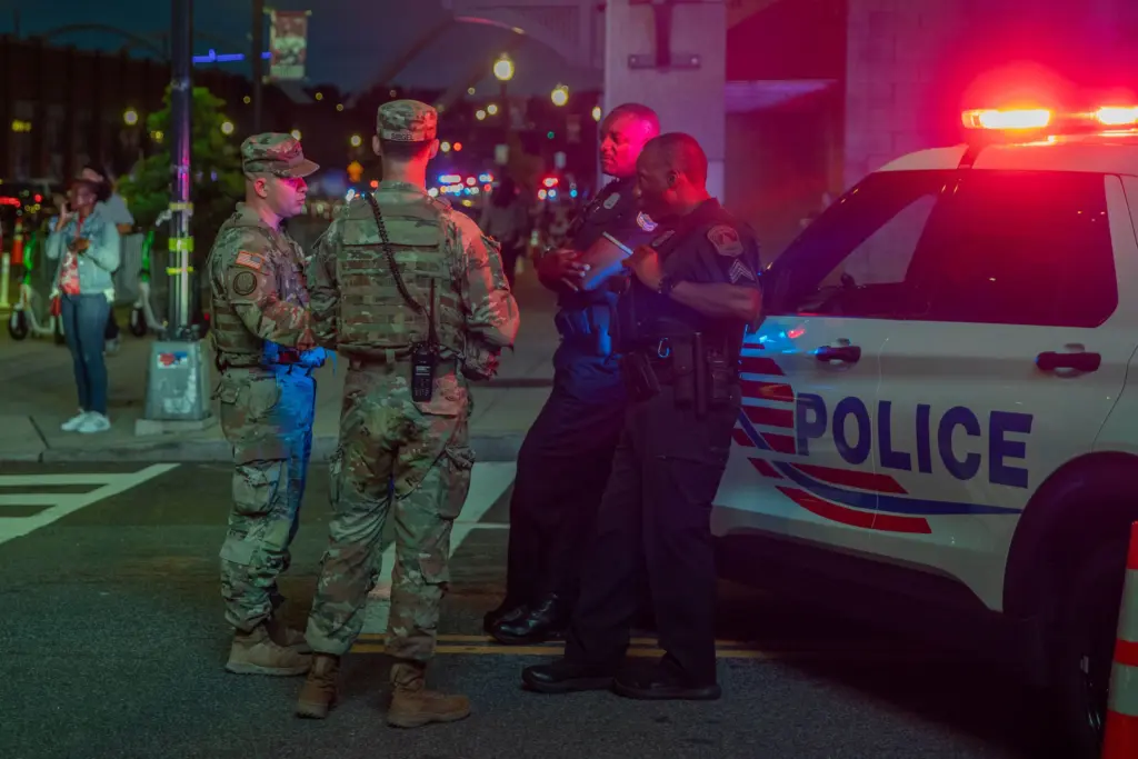 Army 2nd Lt. Harry Siegel and Sgt. 1st Class Nikolay Bashko, both assigned to Joint Task Force District of Columbia as part of the D.C. Safe and Beautiful Task Force, talk with Metropolitan Police Department officers near Nationals Park in Washington, Aug. 19, 2025.