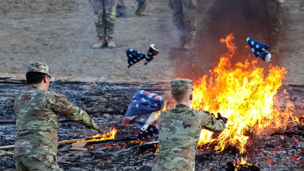 Pfc. Minhyoek Im (left) and Spc. Henry Fetzer (right), Soldiers with 1st Battalion 145th Field Artillery throw unserviceable flags into the fire during the annual Fiesta Days flag retirement ceremony held at the Spanish Fork Rodeo Grounds on July 14, 2025. When flags are no longer serviceable U.S. Flag Code specifies burning as the preferred method to respectfully retire a flag. By Lt. Col. Christopher Kroeber | Utah Army National Guard photo