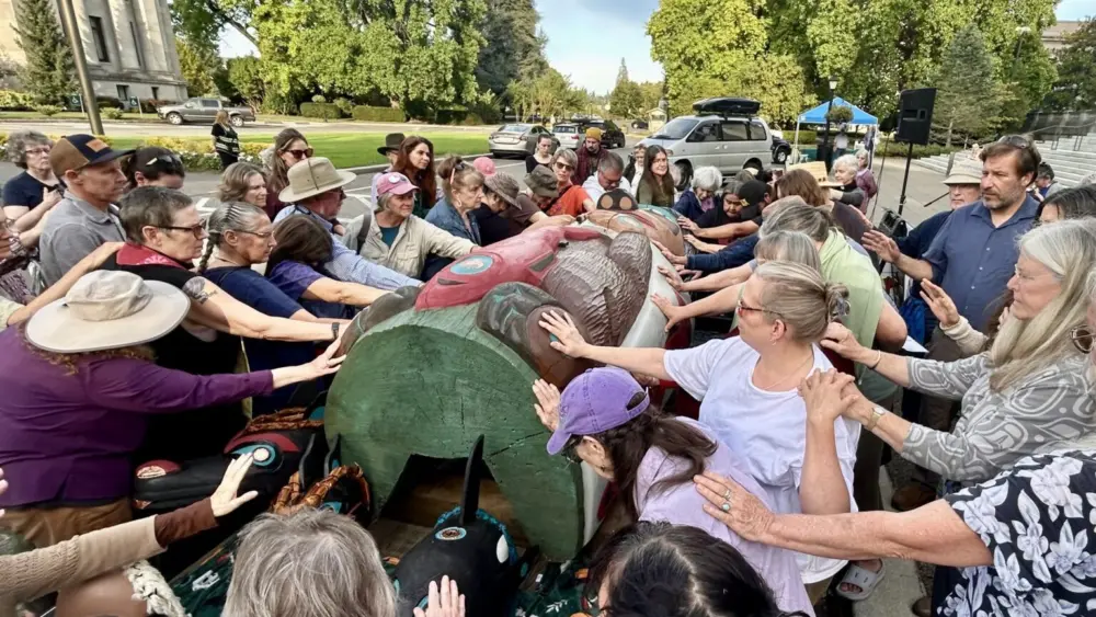 A crowd of about 120 people bless a totem pole and 10 cedar masks carved by the Lummi Nation’s House of Tears outside of the Capitol building in Olympia on Sept. 8, 2025, as part of the Indigenous-led campaign “Xaalh and the Way of the Masks.” The totem and masks will travel 1,700 miles between rally sites in Washington and Oregon before being given to the Lower Elwha Klallam Tribe west of Port Angeles on Sept. 20. (Photo by Emily Fitzgerald/Washington State Standard).