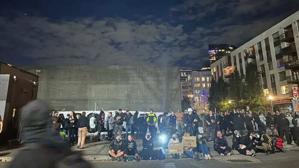 Protesters sit under a dissipating cloud of chemical irritants outside the Portland Immigration and Customs Enforcement building on Saturday, Oct. 4. (Photo by Alex Baumhardt/Oregon Capital Chronicle)