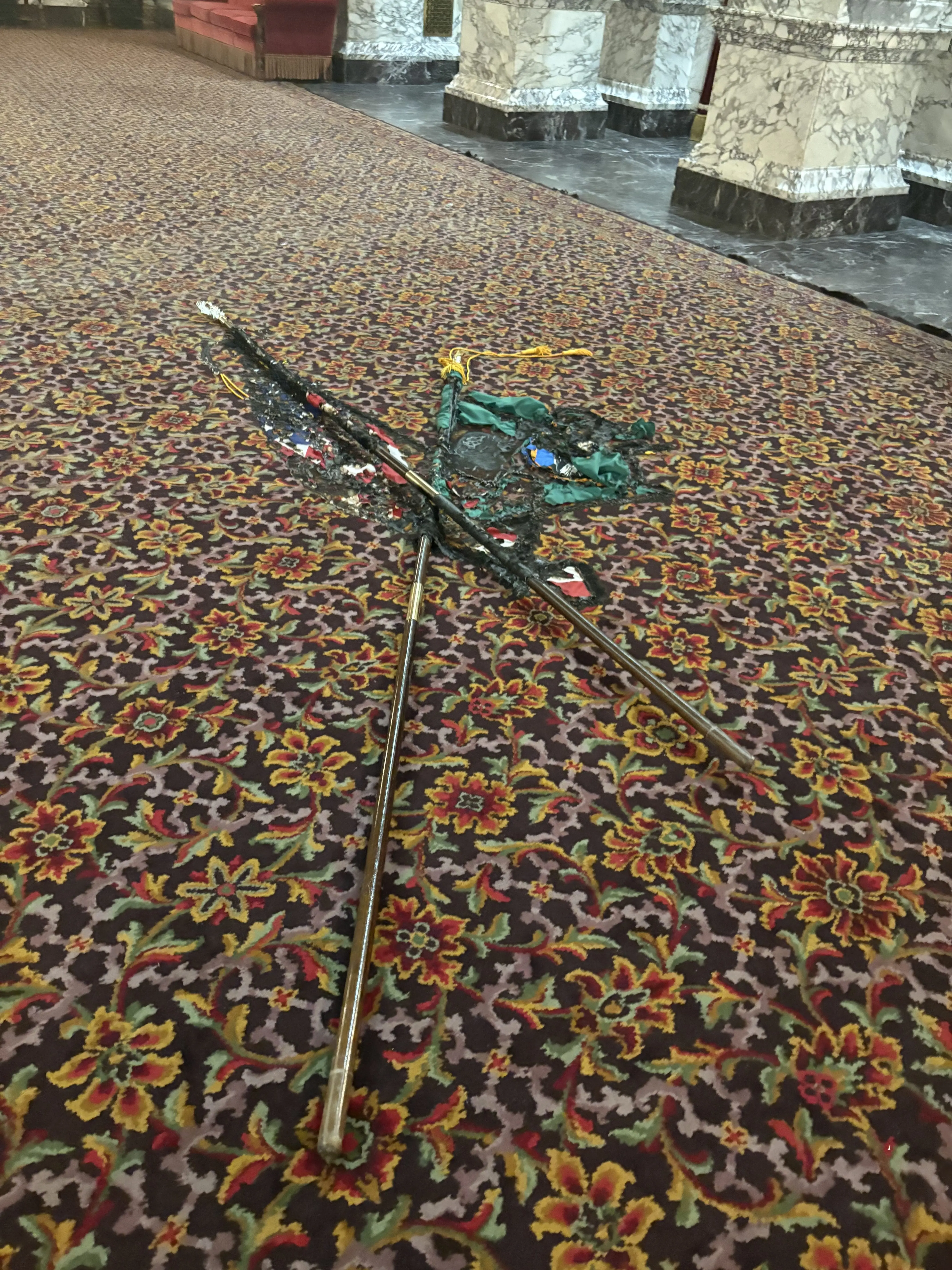 Burned flagpoles and remnants of damaged flags are seen on the floor of the State Reception Room inside the Washington State Capitol. Photo Credit: Washington State Department of Enterprise Services