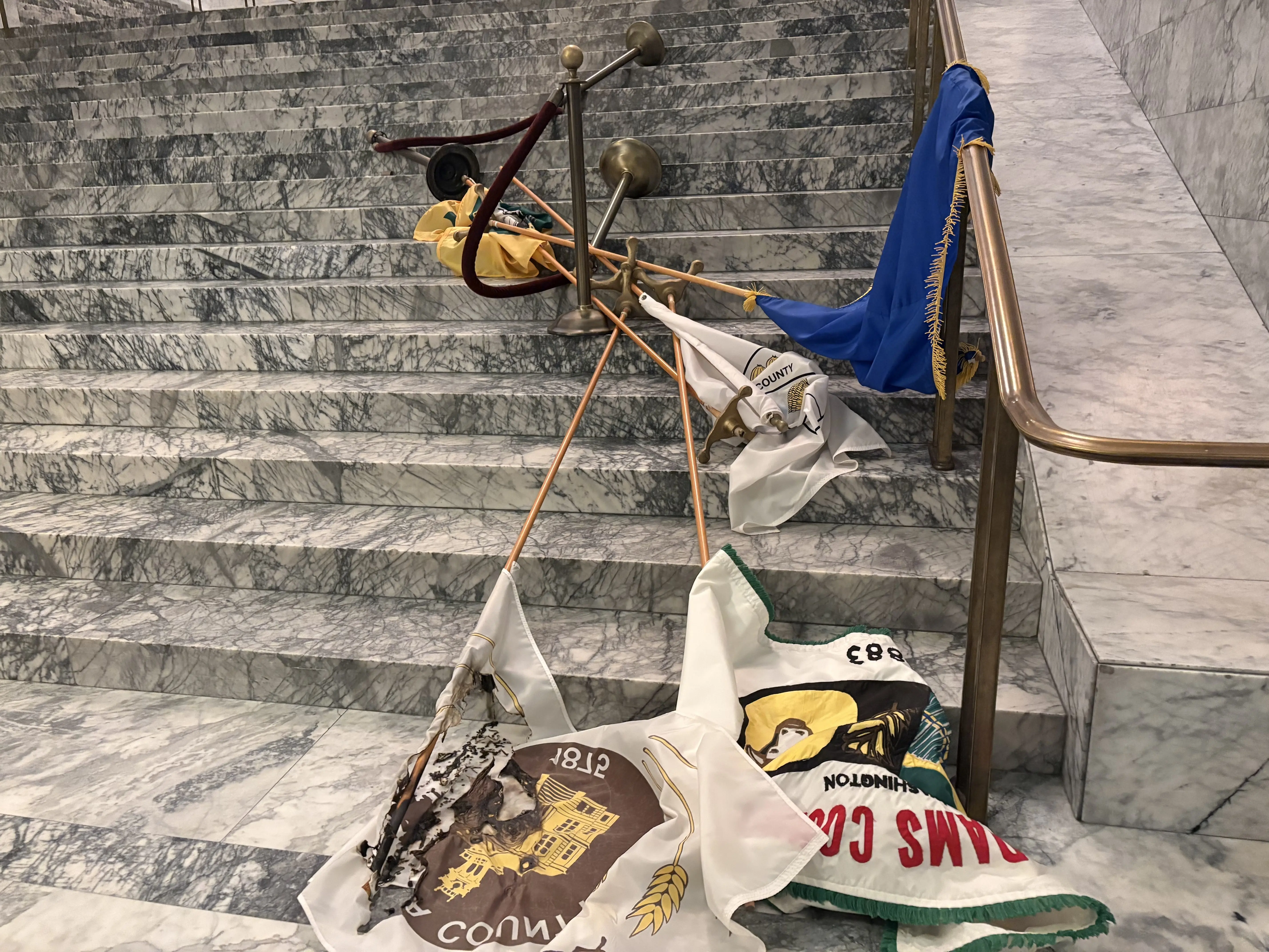 Burned and torn county flags lay scattered on the Capitol’s main staircase after being damaged during the October 5 vandalism. Photo Credit: Washington State Department of Enterprise Services