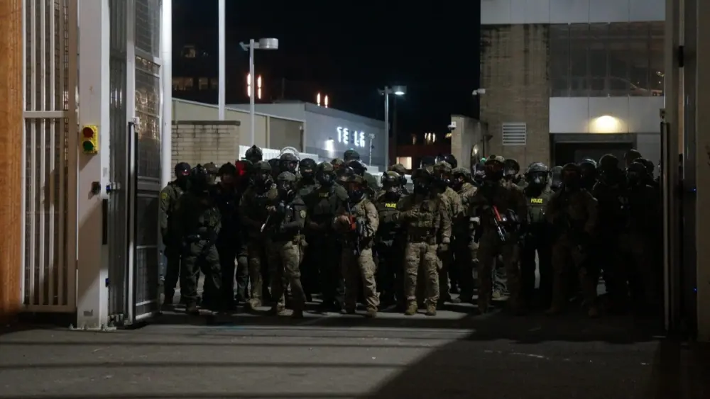 Federal police wait inside the gate of the Immigration and Customs Enforcement processing center south of downtown Portland during protests on Sunday, Oct. 6, 2025. (Photo by Alex Baumhardt)